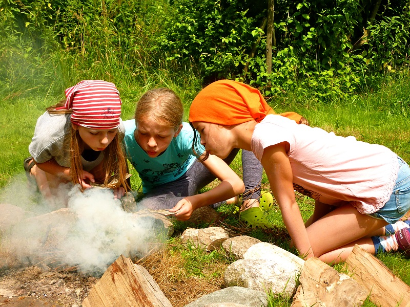 Kinder lernen Feuer anzumachen im Wildniscamp auf dem Ferienhof Grafel